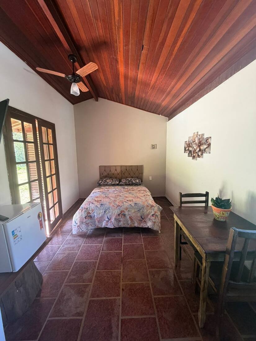 Suíte com cama de casal e mesa de madeira